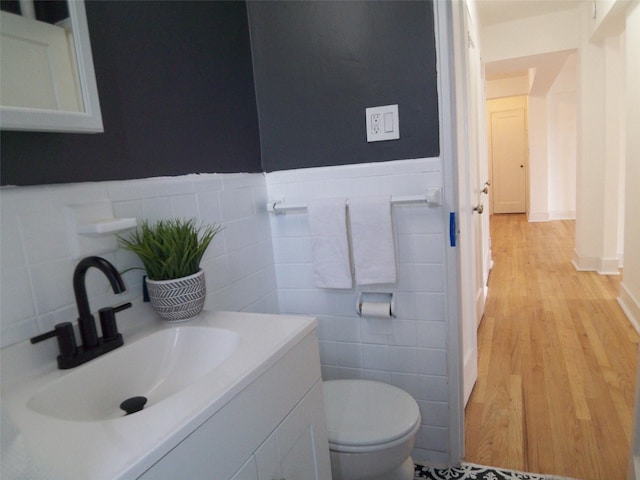 half bath featuring wainscoting, toilet, vanity, and wood finished floors