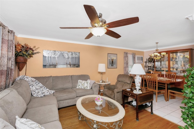 living room with ceiling fan with notable chandelier, ornamental molding, and light wood-style floors