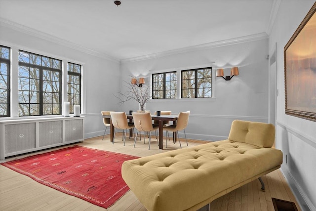 dining room featuring visible vents, baseboards, ornamental molding, radiator, and hardwood / wood-style floors