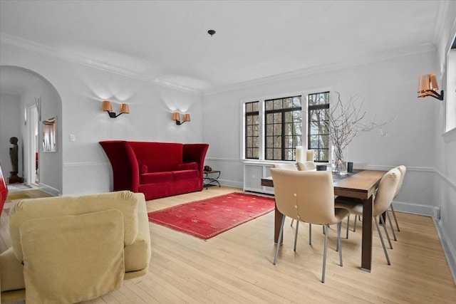 dining area with baseboards, crown molding, arched walkways, and wood finished floors