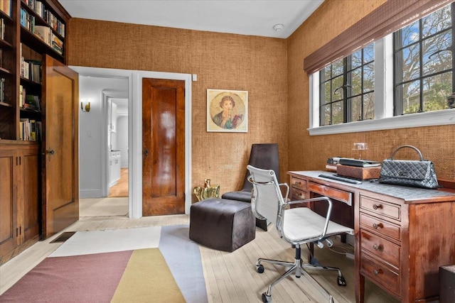 home office with visible vents, light wood-style flooring, and wallpapered walls