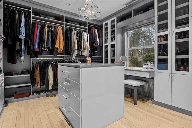 walk in closet featuring a chandelier and hardwood / wood-style floors