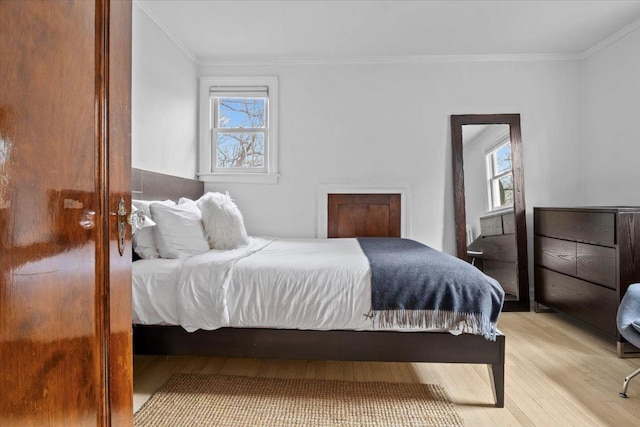 bedroom featuring multiple windows, crown molding, and light wood-style flooring