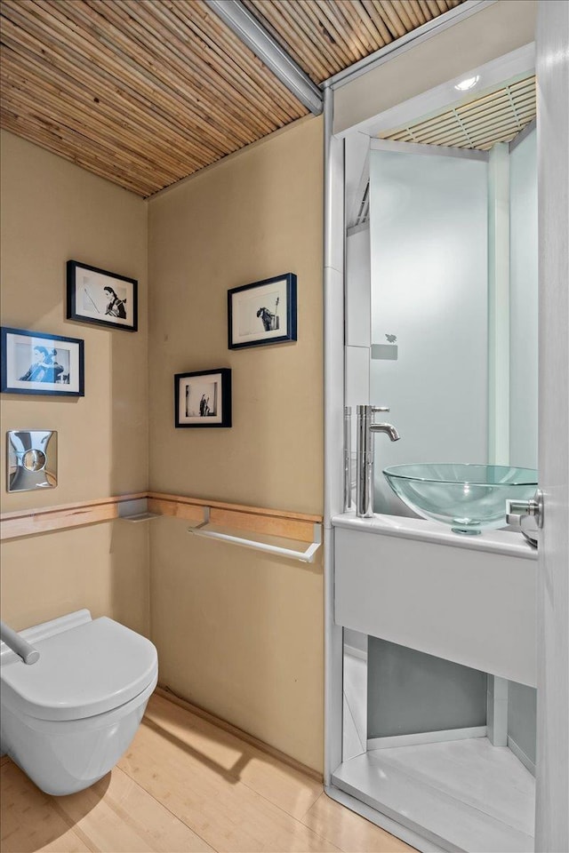 bathroom with wooden ceiling, a sink, and toilet