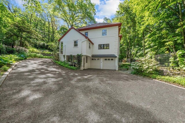 2737 Palisade Ave, Bronx, NY 10463 - view of side of home with asphalt driveway, an attached garage, and stucco siding