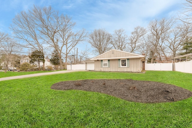 back of property with concrete driveway, a lawn, and fence