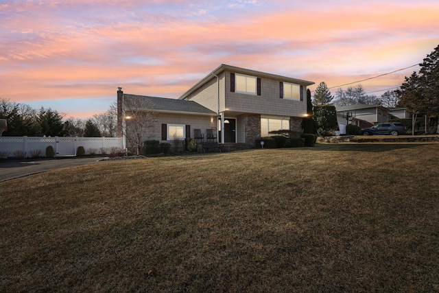 view of front facade with stone siding, fence, and a front lawn