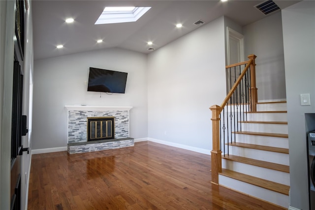 unfurnished living room featuring visible vents, stairway, a glass covered fireplace, wood finished floors, and baseboards