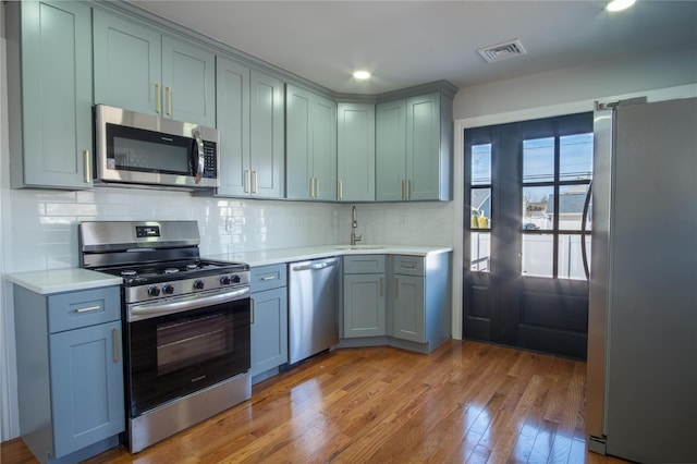 kitchen featuring stainless steel appliances, light countertops, a sink, and visible vents