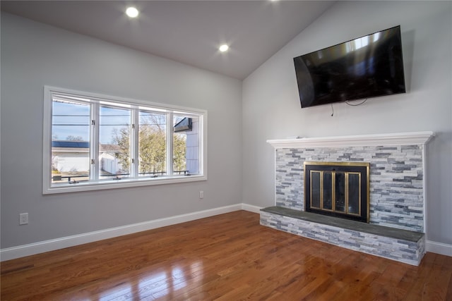 unfurnished living room with lofted ceiling, a fireplace, baseboards, and wood finished floors