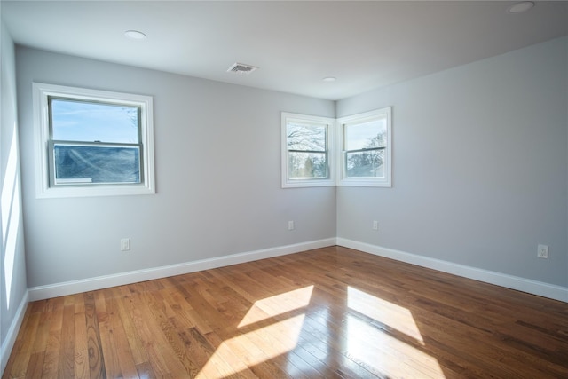 spare room featuring visible vents, baseboards, and wood finished floors