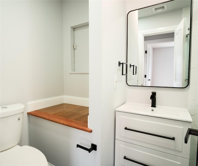 half bath featuring toilet, visible vents, and vanity