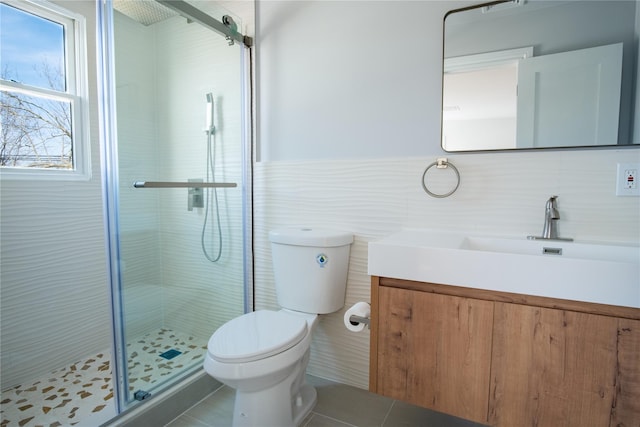 bathroom with toilet, tile patterned floors, vanity, a shower stall, and tile walls