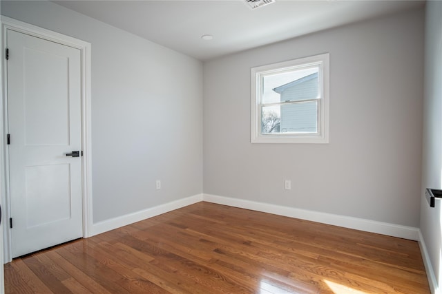 empty room with visible vents, baseboards, and wood finished floors