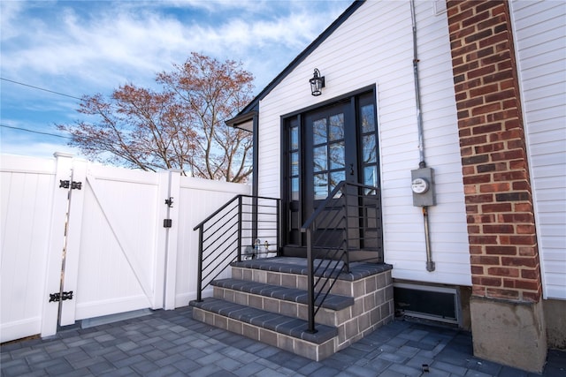 entrance to property with a gate, brick siding, and fence