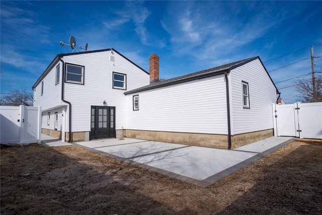 rear view of house with a patio, french doors, fence, and a gate