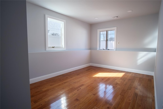 spare room featuring visible vents, baseboards, and hardwood / wood-style floors