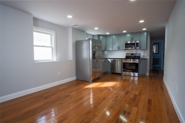 kitchen featuring wood finished floors, visible vents, baseboards, appliances with stainless steel finishes, and backsplash