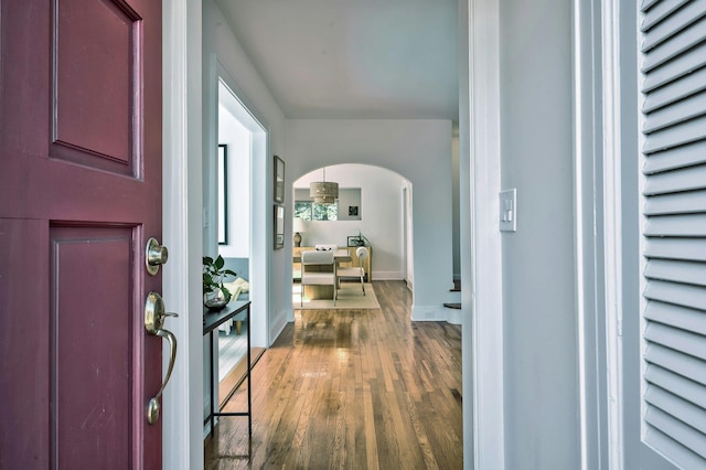 foyer entrance with arched walkways, wood finished floors, and baseboards