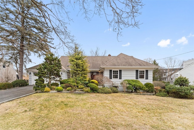 view of front facade with a garage, driveway, a chimney, and a front lawn