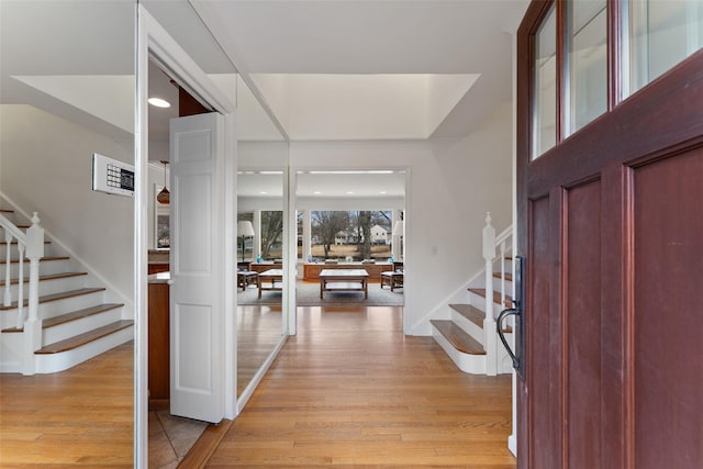 entryway featuring baseboards, light wood finished floors, and stairs