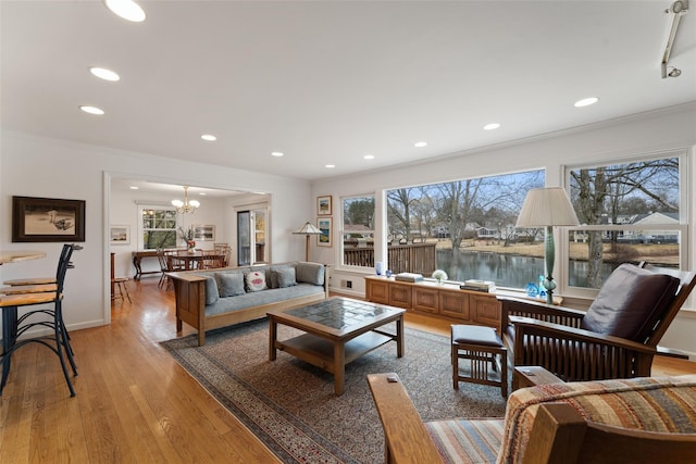 living area featuring light wood-style floors, recessed lighting, ornamental molding, and an inviting chandelier