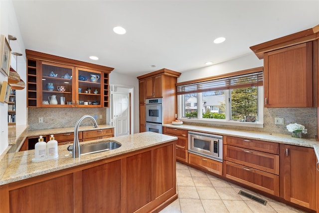 kitchen featuring light tile patterned floors, visible vents, appliances with stainless steel finishes, light stone counters, and a sink