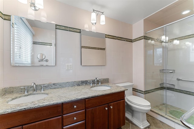 bathroom featuring a sink, tile walls, toilet, and double vanity