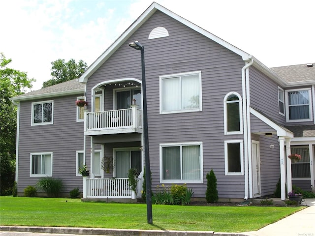 view of property with a front yard and a balcony