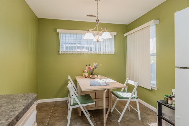 dining room featuring a chandelier, visible vents, dark tile patterned floors, and baseboards