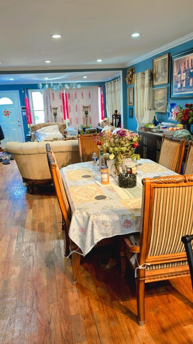 dining space featuring wood-type flooring, ornamental molding, and recessed lighting