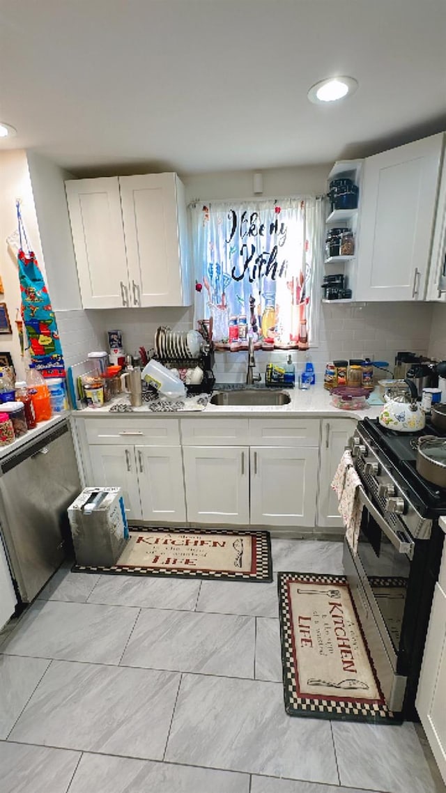 kitchen featuring open shelves, stainless steel appliances, light countertops, white cabinets, and a sink