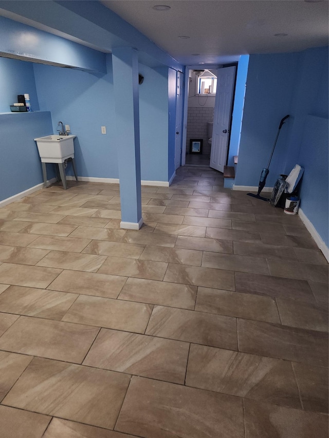 finished basement with baseboards, a sink, and tile patterned floors