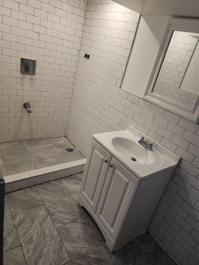 bathroom with a stall shower, marble finish floor, vanity, and tile walls