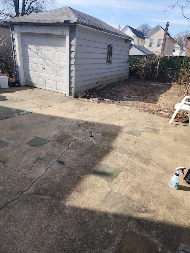 detached garage featuring concrete driveway and fence