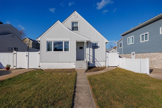 bungalow featuring entry steps, a gate, fence, and a front yard