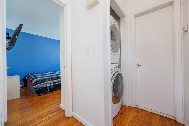 laundry room featuring stacked washer and dryer, light wood-style flooring, and laundry area