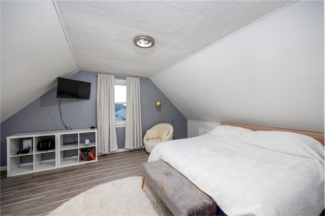 bedroom featuring dark wood-type flooring, vaulted ceiling, and a textured ceiling