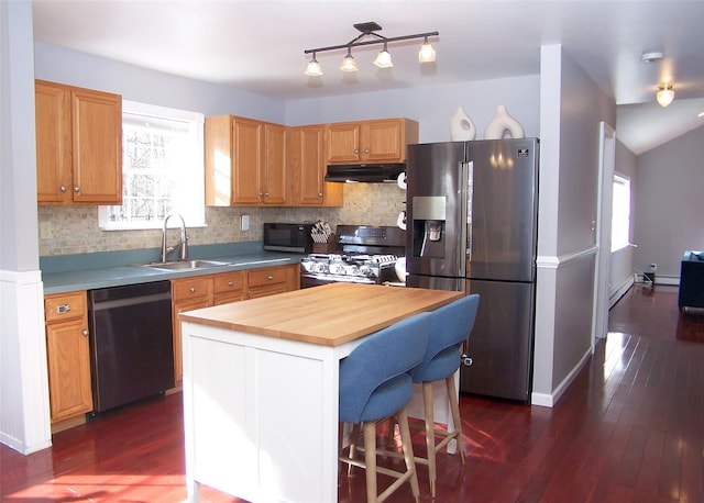 kitchen with under cabinet range hood, stainless steel refrigerator with ice dispenser, a center island, dishwasher, and gas stove