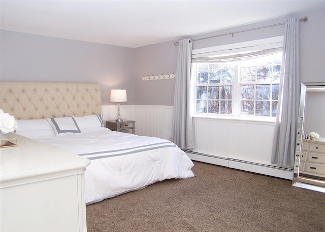 bedroom with a baseboard radiator, dark colored carpet, and wainscoting