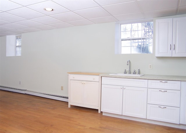 kitchen with a baseboard radiator, light wood-style flooring, a sink, white cabinetry, and light countertops