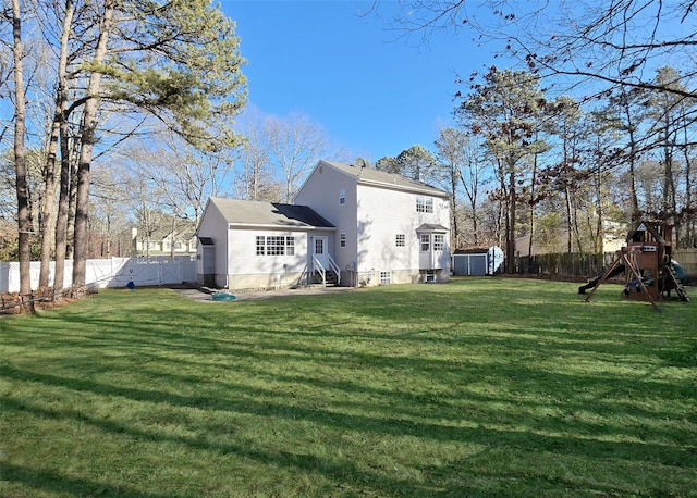 rear view of house featuring entry steps, a lawn, a playground, and a fenced backyard