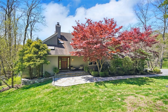 rear view of property with a lawn, a chimney, and a shingled roof