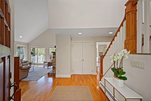 entrance foyer with stairway, high vaulted ceiling, a baseboard heating unit, light wood-style floors, and recessed lighting