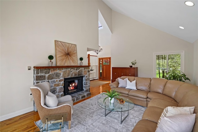 living room featuring a fireplace, wood finished floors, baseboards, high vaulted ceiling, and recessed lighting