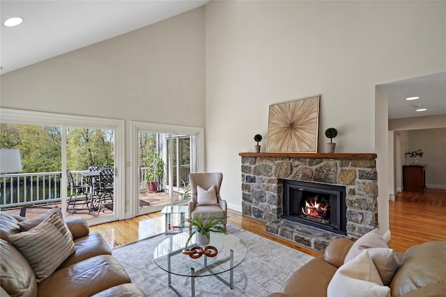 living room with wood finished floors, high vaulted ceiling, baseboards, and a fireplace