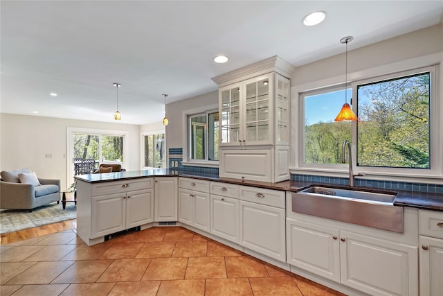 kitchen featuring a peninsula, dark countertops, open floor plan, recessed lighting, and a sink