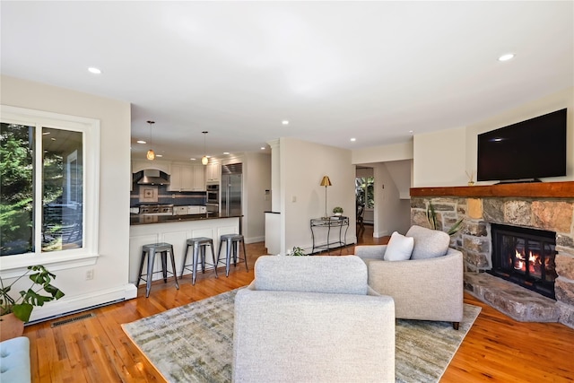 living area with recessed lighting, light wood-style flooring, and a fireplace