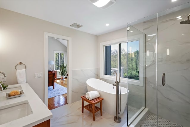 full bath featuring visible vents, tile walls, recessed lighting, a soaking tub, and a marble finish shower