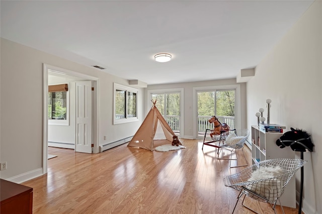 game room with baseboard heating, light wood finished floors, and visible vents